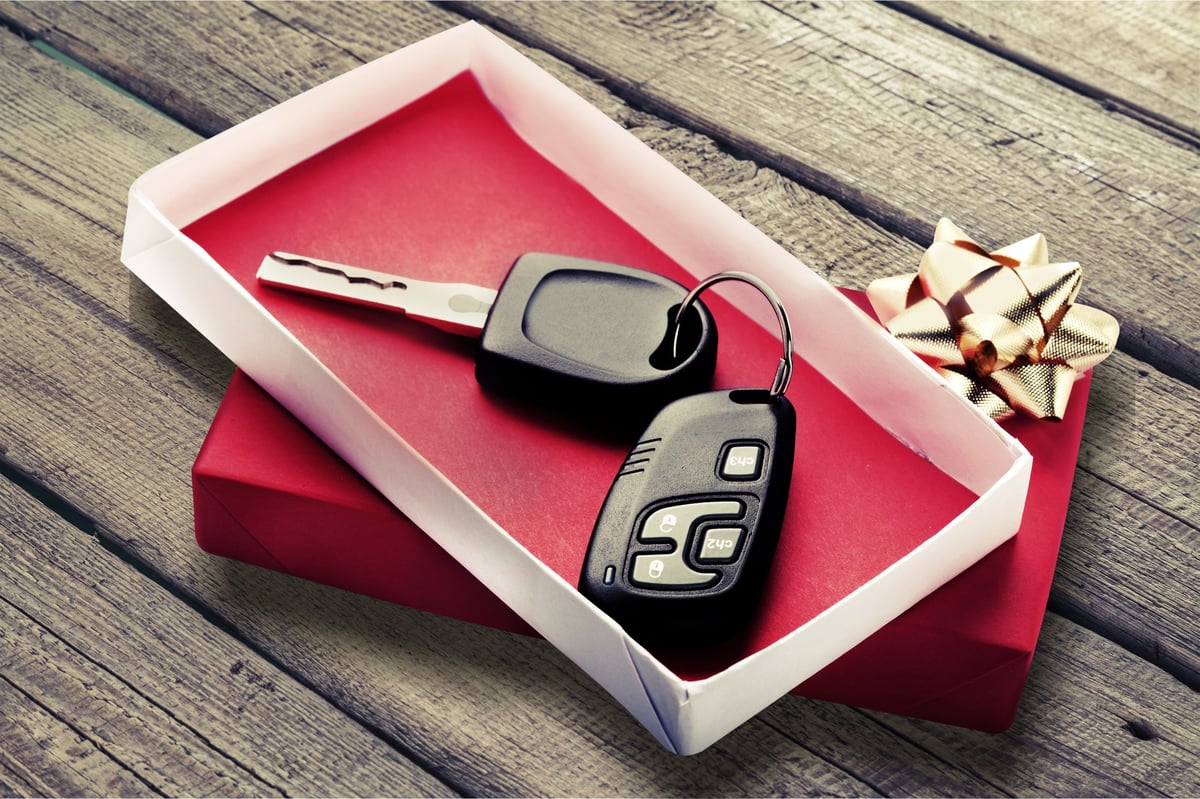Modern Car keys as a gift on background